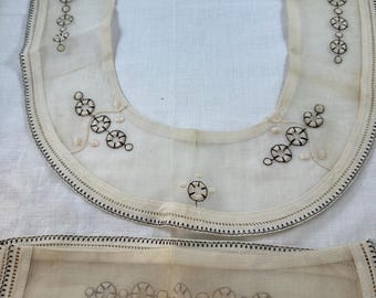 Colletto e polsini neri e crema con bordo decorato.