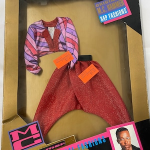 May include: A red and purple striped shirt and red pants for a doll. The packaging features a photo of M.C. Hammer and the text "Original M.C. Hammer Rap Fashions".