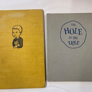 May include: Two vintage children's books with yellow and gray covers. The book on the left has a black and white illustration of a child holding a small animal. The book on the right has the title "The Hole in the Tree" in blue text.