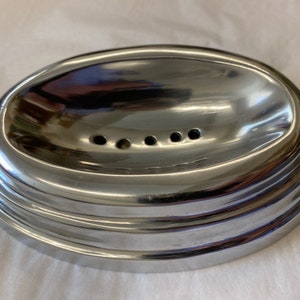 May include: A silver oval-shaped soap dish with a raised rim and five drainage holes.