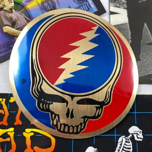 Grateful Dead 1990GDM metal spinner, 2 Refrigerator magnets. 1 bumper sticker and 1 metal Steal Your Face Sticker. Lot