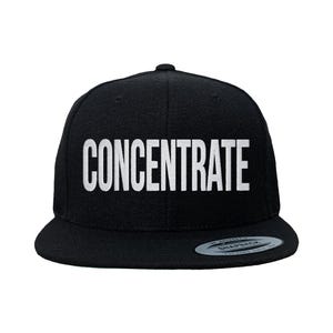 Puede incluir: Gorra snapback negra con la palabra "CONCENTRATE" en letras blancas. La gorra tiene una visera plana y un cierre ajustable a presión. Un accesorio moderno para un look casual.