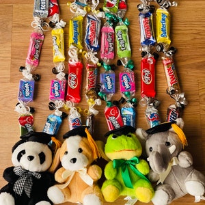 Op de afbeelding: Vijf pluche speelgoed met een afstudeerthema met afstudeerhoeden en kwastjes. Elk speelgoed houdt een snoepketting vast gemaakt van verschillende chocolade- en snoeprepen, waaronder Airheads, Butterfinger, Kit Kat, Twix en Laffy Taffy.