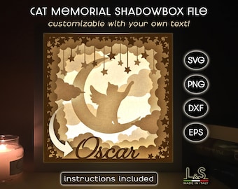 May include: A brown wooden shadowbox with a cut-out design of a cat sleeping on a crescent moon with stars. The cat's name "Oscar" is written below the moon. The shadowbox is customizable with your own text.