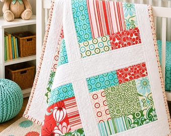 May include: A patchwork quilt featuring a variety of fabric squares in red, green, and teal colors. The quilt displays patterns including floral motifs, stripes, and circular designs, all separated by white fabric borders with a stitched texture.