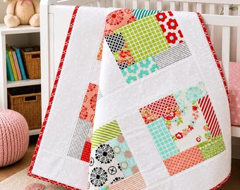 May include: A patchwork baby quilt featuring a variety of colorful fabric squares in shades of red, green, teal, and black, separated by white fabric panels. The quilt is finished with a bright red patterned border and white backing fabric.