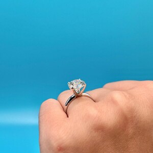 May include: A silver engagement ring with a large, round, clear diamond set in a prong setting.
