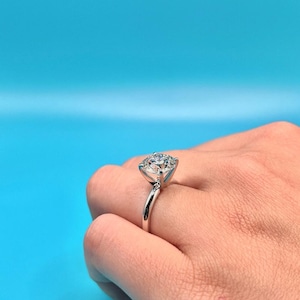 May include: A silver ring with a large, clear, round diamond solitaire.