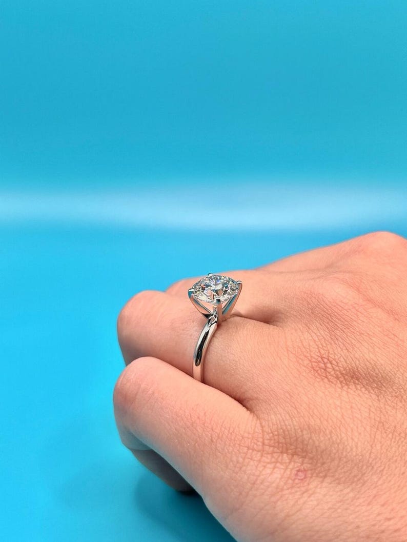 May include: A silver ring with a large, clear, round diamond solitaire.