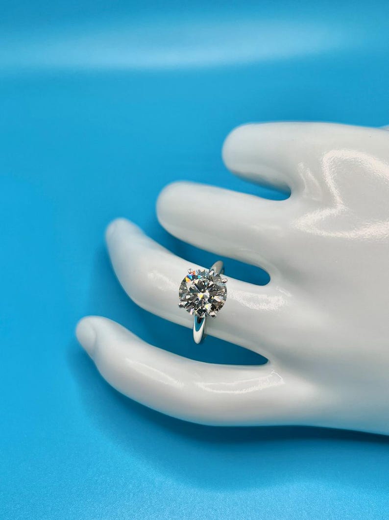 May include: A silver solitaire engagement ring with a large, round, clear diamond set in a simple band.