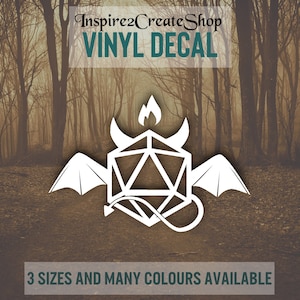 Pode incluir: Adesivo de vinil branco com um design geométrico de diabo com asas, chifres e uma chama. O texto "Inspire2CreateShop VINYL DECAL" está no topo e "3 TAMANHOS E MUITAS CORES DISPONÍVEIS" na parte inferior. Fundo de floresta.