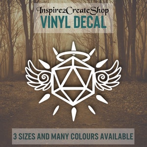 Pode incluir: Adesivo de vinil branco de um dado de 20 faces com asas de anjo e um halo. O adesivo diz "Inspire2CreateShop VINYL DECAL" na parte superior e "3 SIZES AND MANY COLOURS AVAILABLE" na parte inferior.
