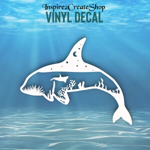 Pode incluir: Autocolante de vinil branco com a silhueta de uma orca com uma cena subaquática no interior. A cena inclui uma baleia, corais e plantas, com uma lua e estrelas no topo. O texto no topo diz "Inspire2CreateShop VINYL DECAL".