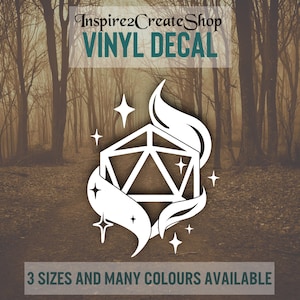 Pode incluir: Adesivo de vinil branco com um design de dado D20, chamas e estrelas. O texto diz "Inspire2CreateShop VINYL DECAL" e "3 SIZES AND MANY COLOURS AVAILABLE". Fundo desfocado de floresta.