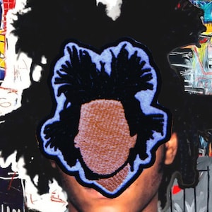 May include: A rectangular embroidered patch featuring a stylized, faceless head with dark, spiky hair outlined in light blue thread against a tan background. The patch is layered over a dark, abstract, and expressive artistic background.