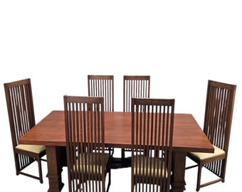 Puede incluir: Una mesa de comedor rectangular de madera con un acabado marrón cálido y cuatro patas robustas, acompañada de seis sillas a juego de respaldo alto. Cada silla presenta un diseño de listones verticales y un cojín de asiento beige claro.