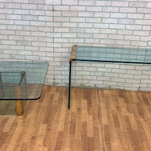 May include: Two glass and brass tables with clear glass tops. The larger table is rectangular and the smaller table is square.