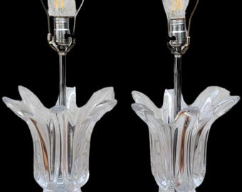 Puede incluir: Par de lámparas de mesa de cristal transparente con forma de tulipán y detalles cromados. Cada lámpara tiene una bombilla en la parte superior, un tallo cromado y una base con forma de tulipán floreciente. Sobre fondo negro.