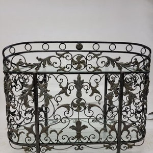 May include: A black metal and glass two-tiered stand with an ornate scroll design. The stand has a rounded top and two glass shelves.