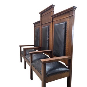 May include: A triple-seat wooden bench featuring a high-backed design with three distinct sections. The frame is constructed from dark brown wood, complemented by black leather upholstery on the seats and backrests, secured with metal nailhead trim.