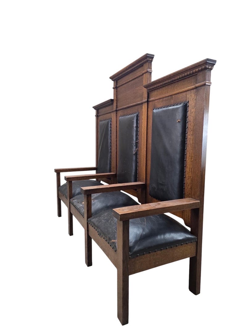 May include: A triple-seat wooden bench featuring a high-backed design with three distinct sections. The frame is constructed from dark brown wood, complemented by black leather upholstery on the seats and backrests, secured with metal nailhead trim.