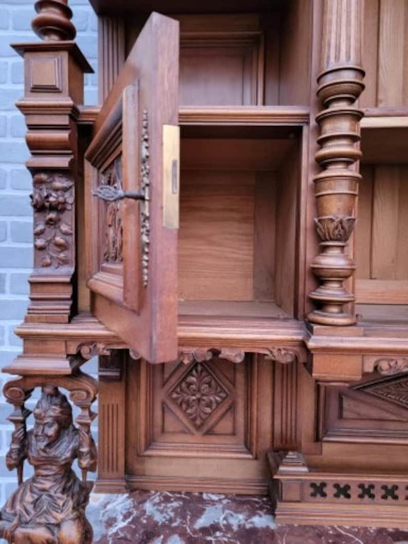 May include: A large, intricately carved wooden cabinet with a glass door and multiple shelves. The cabinet is made of dark wood and has a rich, antique finish.