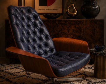 May include: A lounge chair featuring a deep blue, tufted, textured leather seat and backrest, supported by a curved wooden frame and a four-pronged silver metal swivel base. The upholstery has a distinct reptilian-like embossed pattern.