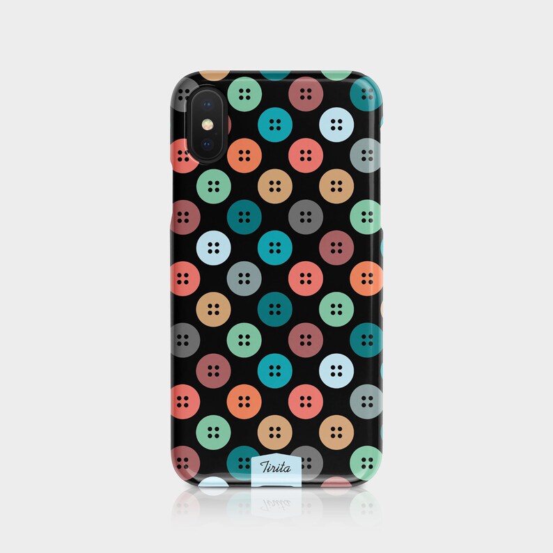 Puede incluir: Una funda de tel&eacute;fono negra con un patr&oacute;n de botones coloridos. La funda tiene una etiqueta blanca con la palabra "Tirista" en ella.