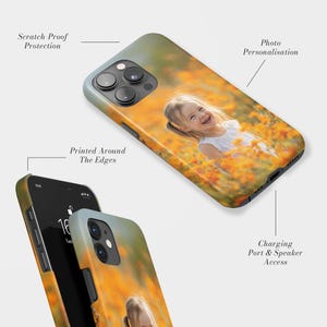 May include: Two phone cases with a photo of a smiling child in a field of orange flowers. The cases have a glossy finish and feature the text "Scratch Proof Protection", "Printed Around The Edges", "Photo Personalisation", and "Charging Port & Speaker Access".