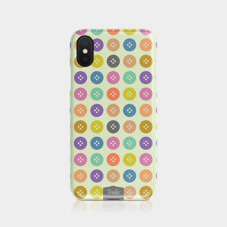 Puede incluir: Una funda de tel&eacute;fono colorida con un patr&oacute;n de botones en varios colores, incluyendo amarillo, naranja, rojo, verde, azul, morado y gris. La funda tiene un fondo blanco y la palabra "Tirita" est&aacute; impresa en la parte inferior.