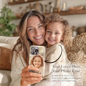 May include: A phone case featuring a photograph of a young girl, held by a woman. The case is cream-colored and has a camera cutout. Text on the image reads "Your Loved Ones, Your Phone Case" and "A one-of-a-kind case that keeps your loved ones right at your fingertips."