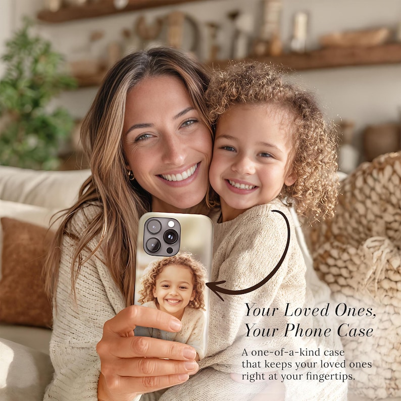 May include: A phone case featuring a photograph of a young girl, held by a woman. The case is cream-colored and has a camera cutout. Text on the image reads "Your Loved Ones, Your Phone Case" and "A one-of-a-kind case that keeps your loved ones right at your fingertips."