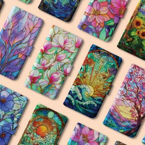 Może przedstawiać: Kolekcja kolorowych etui na telefony z witrażowymi wzorami. Etui mają wzory kwiatowe, krajobrazowe i abstrakcyjne w odcieniach niebieskiego, różowego, zielonego i żółtego. Każde etui ma magnetyczne zamknięcie.