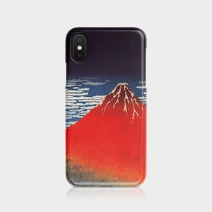 May include: A phone case featuring a vibrant illustration of a red mountain under a dark blue sky with white clouds. The case has a glossy finish and a black border, showcasing a classic Japanese art style.