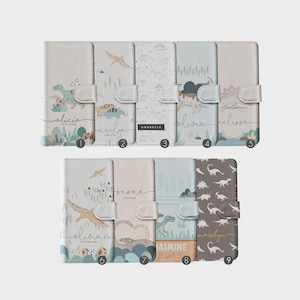 Pode incluir: Nove capas de telefone diferentes com um tema de dinossauros. Cada capa apresenta um design de dinossauro diferente e um nome, como Alicia, Marilyn, Olivia e Jasmine.