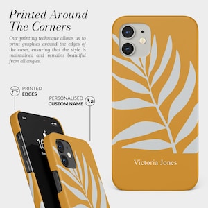 Pode incluir: Capa de telefone amarelo mostarda com um design de folha branca. O nome "Victoria Jones" est&aacute; impresso na parte inferior. O texto "Printed Around The Corners" &eacute; vis&iacute;vel no fundo.