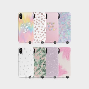 May include: Eight different phone case designs. The cases feature a variety of patterns, including tie-dye, hearts, stars, leaves, and constellations. The text "SHUT UP" is featured on one of the cases.