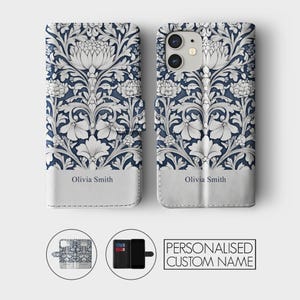 May include: A white and blue floral phone case with a personalized name, "Olivia Smith", printed on the back. The case is made of leather and has a wallet-style design with a slot for cards.