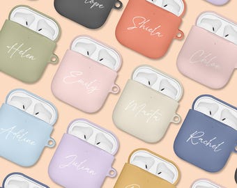 Könnte beinhalten: Sortiment von 12 personalisierten Airpod-Hüllen in verschiedenen Farben, jede mit einem anderen Namen in weißer Schrift. Die Hüllen sind aus Silikon und haben eine kleine Schlaufe zum Anbringen eines Schlüsselanhängers.