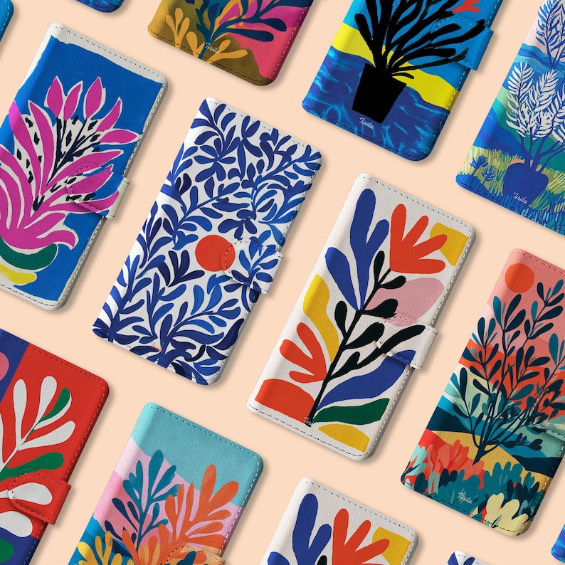 May include: A collection of colorful phone cases with vibrant floral and abstract designs. Each case features a unique pattern in shades of blue, red, yellow, and pink, with a white interior and a magnetic closure.