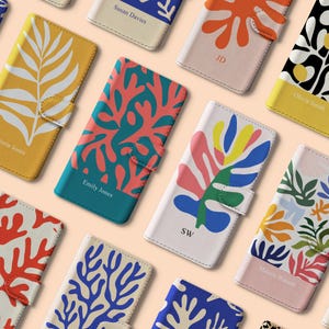 May include: A selection of phone cases with vibrant, abstract floral patterns. The cases display designs in yellow, orange, blue, pink, and green. Some cases are personalised with names or initials.
