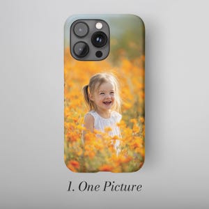 May include: A phone case featuring a photograph of a smiling child in a field of orange flowers. The case has a light blue top and the text "1. One Picture" at the bottom.