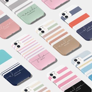 Può includere: Assortimento di custodie per telefono a righe colorate con nomi personalizzati. Ogni custodia presenta una combinazione di colori diversa e un nome scritto in corsivo.