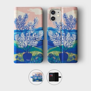 May include: A phone case with a landscape design. The case features a blue vase with white leafed branches, set against a backdrop of blue hills, green fields, and a pink and blue sky. The case is shown open and closed.