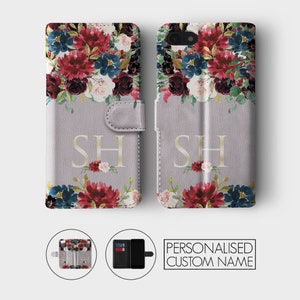 K&ouml;nnte beinhalten: Eine personalisierte Handyh&uuml;lle mit einem Blumendesign in Rot-, Blau- und Wei&szlig;t&ouml;nen. Die H&uuml;lle hat einen grauen Hintergrund und die Initialen "SH" sind in Gold auf der Vorderseite aufgedruckt. Die H&uuml;lle ist geschlossen und ge&ouml;ffnet dargestellt, wobei ein Kartensteckplatz und ein Telefonhalter sichtbar sind.