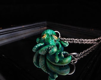 Op de afbeelding: Een groene octopus met witte stippen en gele ogen is een hanger aan een zilveren ketting.