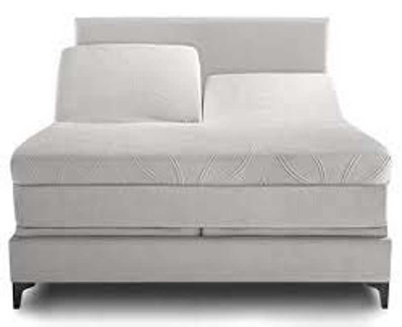 May include: A gray adjustable bed frame with a white mattress and two pillows. The bed frame has a headboard and footboard, and the mattress is covered in a white fabric.