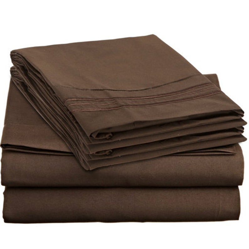 May include: A stack of brown bed sheets with a decorative trim. The sheets are folded neatly and are ready to be used.