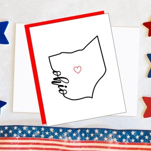 May include: A white card with a red border. The card features a black outline of the state of Ohio with the word "Ohio" written inside the outline. A small red heart is placed inside the outline of the state.