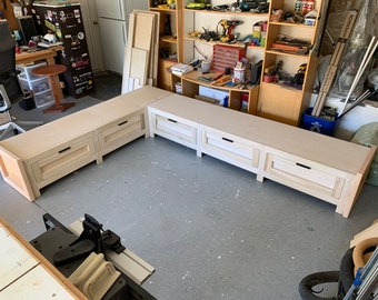 May include: A white wooden bench with drawers, featuring a corner design. The bench is unfinished and has a simple, modern style.